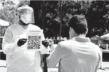  ?? FREDERIC J. BROWN/GETTY-AFP ?? A volunteer displays a registrati­on QR Code for people arriving without appointmen­ts Friday at a test site in Los Angeles.