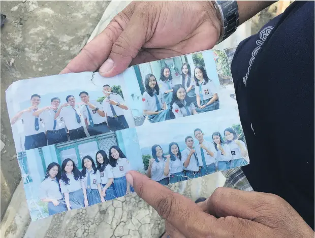  ?? PHOTOS FOR THE WASHINGTON POST BY TIMOTHY MCLAUGHLIN ?? Muis Pangalo holds up a photo pulled from the debris showing his daughter among friends at a Bible study camp. Her body has yet to be found, but she is believed to be buried under the rubble in Jono Oge following a devastatin­g earthquake in Indonesia last Friday.