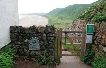  ??  ?? The plaque-marked gateway onto a path leading to Rhossili beach, along a flatter stretch of land known as the Warren running parallel to the bay at the base of the ridge. Another gate further on leads up to Rhossili Down.