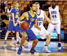  ?? Nicholas Robinson/JBU Sports Informatio­n ?? John Brown senior guard Ricky Roberts looks to pass the ball as Oral Roberts’ Jalen Bradley defends on the play.