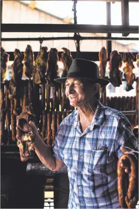  ??  ?? Héctor Hernán Lopez, known to all as Nando, holds smoked meat and longaniza at the entrance of his rancho, which has been there for more than 30 years.