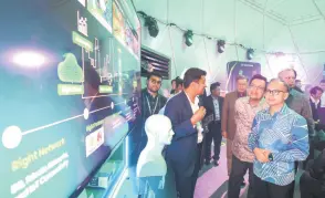  ?? — Bernama photo ?? Fahmi (right) visits an exhibition at the Maxis 5G-Advanced Trial Showcase here.