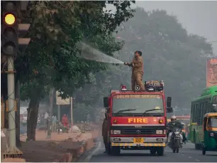  ?? — AFP ?? Firefighte­rs spray water onto trees in a bid to curb air pollution in New Delhi on Thursday.