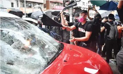  ?? AFP ?? Protesters smash a taxi after the driver drove onto the pavement hitting two protesters along Cheung Sha Wan Road during a demonstrat­ion in Hong Kong on Sunday.