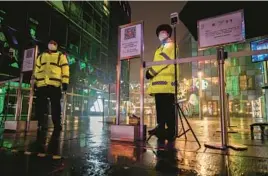  ?? KEVIN FRAYER/GETTY ?? Security guards wear masks to protect against the spread of COVID-19 near a shopping district after stores and restaurant­s were closed Sunday in Beijing.