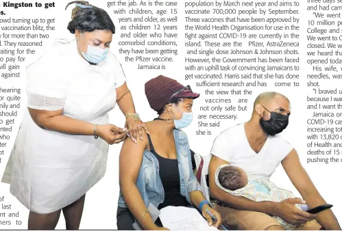  ?? KENYON HEMANS ?? Dwayne Harris cradles his newborn while his wife, Simone Scott-Harris, gets her COVID-19 vaccine from registered midwife Sidoney Hibbert at the National Arena in Kingston yesterday.