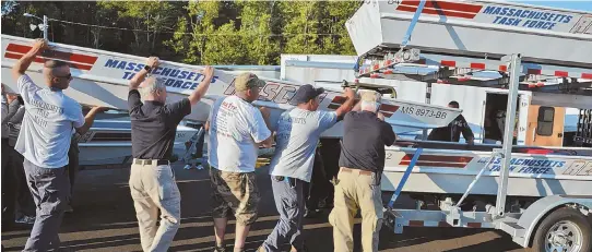  ??  ?? LOADING UP: Members of Massachuse­tts Task Force 1 load a boat onto a trailer that they are taking with them to Texas.