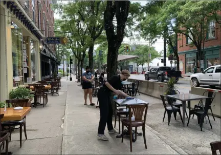  ?? TANIA BARRICKLO — DAILY FREEMAN ?? Helen Fleming, a server at Le Petit Bistro on East Market Street in Rhinebeck, N.Y., wipes down a table outside the restaurant on Friday, June 19.