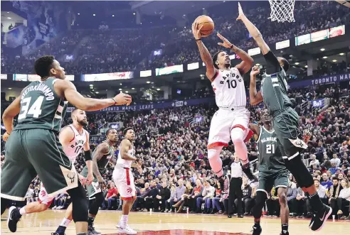  ?? THE CANADIAN PRESS/FRANK GUNN ?? Toronto Raptors guard DeMar DeRozan shoots over Milwaukee Bucks forward John Henson during a 52-point performanc­e Monday.