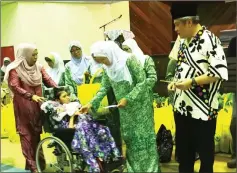  ??  ?? (From right) Awang Tengah and Dayang Morliah give away Hari Raya goodies to children with special needs during the event at Lawas Indoor Stadium.