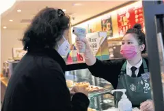  ?? REUTERS ?? ABOVE
A worker uses a thermomete­r to check the temperatur­e of a customer as she enters a Starbucks shop in Beijing.