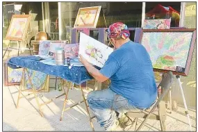  ?? (NWA Democrat-Gazette/Susan Holland) ?? Surrounded by several of his finished works, Gravette artist Jim Holland works on one of his colorful abstract art paintings at the third Thursday gallery walk June 17 on Gravette Main Street. Holland was born in California and served a tour of duty in the Marine Corps in Puerto Rico. He moved to Arkansas from Arizona about 15 years ago.