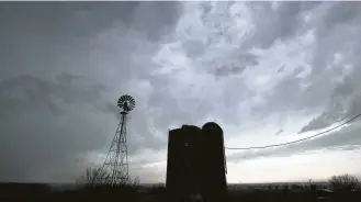  ?? Orlin Wagner / Associated Press ?? Thundersto­rms pass over silos and a windmill near Baldwin City, Kan., on Friday. The area was under a severe thundersto­rm warning.