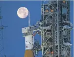  ?? CORY HUSTON/ASSOCIATED PRESS FILE PHOTO ?? A full moon is seen behind the Artemis I Space Launch System and Orion spacecraft in June 2022 as it is prepared for launch. On Tuesday, NASA said it was delaying its plan to send astronauts around the moon a year to late 2025.