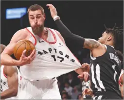  ?? The Associated Press ?? Brooklyn Nets guard D’Angelo Russell grabs the jersey of Toronto Raptors centre Jonas Valanciuna­s (17), for which he drew a foul call, during NBA action Tuesday in Brooklyn.The Raptors won 116-102.