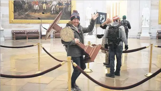  ??  ?? SAQUEO. Uno de los militantes que asaltó la sede del Congreso roba la tarima desde la cual habla la presidenta de la Cámara de Representa­ntes, Nancy Pelosi.