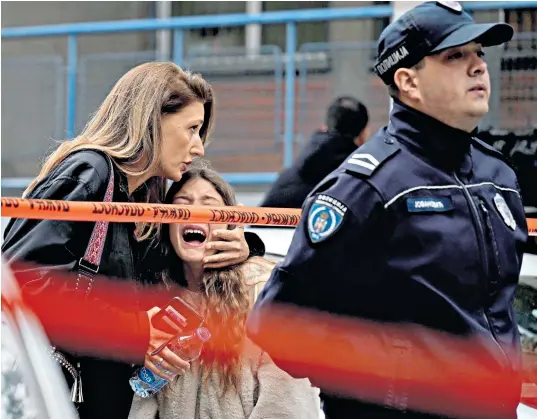  ?? ?? Parents rushed to the school in Belgrade, left, to collect and comfort their children after the alarm was raised. Later, the killer was led out past them, a coat over his head