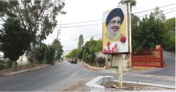  ?? ( Aziz Taher/ Reuters) ?? CARS DRIVE near a poster depicting Hezbollah leader Hassan Nasrallah at the entrance of the village of Ain Qana, Lebanon, yesterday.