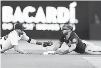  ?? WILFREDO LEE/AP ?? Marlins shortstop Miguel Rojas, left, attempts to tag the Nationals’ Luis Garcia after Garcia hit a double during the fourth inning of Tuesday’s game in Miami.