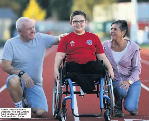  ??  ?? Robbie Jones with his new wheelchair from the Sunshine Fund, with his grandparen­ts Sandra and John Graham