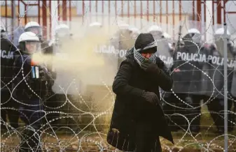  ?? Leonid Shcheglov / Associated Press ?? Polish security forces spray tear gas during clashes between migrants and border guards at the Belarus-Poland border. Border forces say they were attacked with stones by migrants.