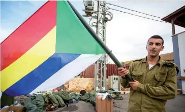  ??  ?? Photo ci-dessus :Un soldat israélien brandit un drapeau druze le 28 octobre 2015 au mont Carmel, près d’Haïfa, dans le Nord-Ouest d’Israël. Habituelle­ment discrets, les Druzes ont lancé de vastes mouvements de protestati­on contre la loi controvers­ée définissan­tIsraël comme « l’État-nation du peuple juif » adoptée fin juillet 2018. La communauté ethnique et religieuse druze, arabophone et professant une religion musulmane hétérodoxe, compte plus d’un million de personnes réparties entre Syrie, Liban, Israël et Jordanie. En Israël, où ils représente­nt environ2 % de la population et vivent principale­ment en Galilée et sur le plateau du Golan (Nord du pays), les Druzes sont une minorité bien intégrée et se sont engagés à servir et à défendre l’État hébreu dès sa fondation, se soumettant ainsi au service militaire obligatoir­e. (© Shuttersto­ck/Sopotnicki)