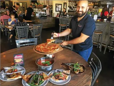  ?? GARY PULEO — DIGITAL FIRST MEDIA ?? Anthony’s Coal Fired Pizza regional manager Anthony Sandstrom showcases a variety of menu items at the chain’s newest restaurant in Blue Bell, including the signature coal-fired pizza, Pot of Meatballs and Eggplant Marino, named after co-owner and...