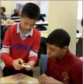  ?? CHINA DAILY ZHANG RUINAN / ?? A student from Beijing shows a student at Medgar Evers College Preparator­y School in Brooklyn, New York how to do traditiona­l Chinese paper-cutting and calligraph­y during a cultural exchange event in New York on Friday.