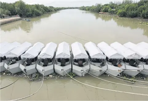  ?? PHOTOS BY WICHAN CHAROENKIA­TPAKUL ?? Navy boats line up across the river in Ban Laem district of Phetchabur­i. Their engines can help push floodwater out to sea.