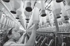  ?? ZHUO ZHONGWEI / FOR CHINA DAILY ?? line at a textile factory in Yushan, Jiangxi province.
Center: A worker checks a polyester yarn production