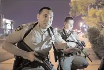  ?? The Associated Press ?? Police officers advise people to take cover near the scene of a shooting near the Mandalay Bay resort and casino on the Las Vegas Strip on Sunday.