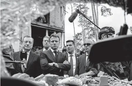  ?? Ludovic Marin/Associated Press ?? Italian Prime Minister Mario Draghi, left, and French President Emmanuel Macron look at debris as they visit Irpin, outside Kyiv. Leaders of France, Germany, Italy and Romania arrived in Kyiv on Thursday in a show of collective European support.