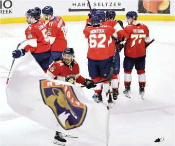  ?? PHOTOS BY DAVID SANTIAGO dsantiago@miamiheral­d.com ?? Ryan Lomberg carries the team banner and victory rats hit the ice as the Panthers celebrate their 11th consecutiv­e win at home after Aaron Ekblad (5) scored the winning goal in overtime.