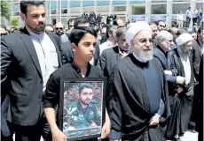  ?? GETTY IMAGES ?? Iran’s President Hassan Rouhani walks alongside the relative of a victim of twin attacks in Tehran earlier in the week during a funeral in the capital.