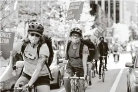  ?? Photos by Jason Redmond / Getty Images ?? Seattle employees of Amazon, its supermarke­t subsidiary Whole Foods and supermarke­t delivery services were called to strike on May Day.