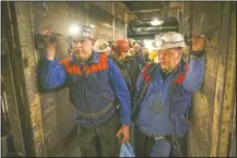  ??  ?? Miners hold bags of food as they stand in an elevator taking them undergroun­d.