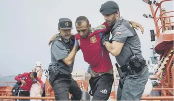  ??  ?? A would-be immigrant is helped by Spanish Guardia Civil policemen in the port of Tarifa following his rescue by salvage vessels off the Strait of Gibraltar coast. Eighty-eight Moroccans were saved, of whom 20 were children