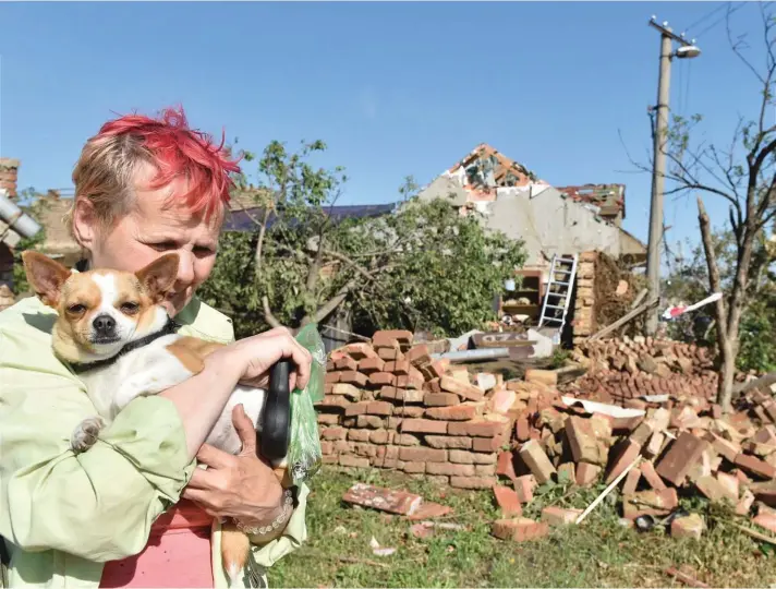  ??  ?? A woman with her dog cries in front of her damaged house after a tornado hit the village of Moravska Nova Ves in the Breclav district, South Moravia, Czech Republic. A rare tornado tore through southeaste­rn Czech Republic, killing a few people and injuring hundreds, rescue services said on Friday.