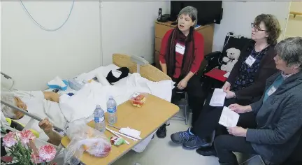  ??  ?? Threshold Singers Kathryn Green, left, Chris Lindgren and Patti Soltys sing songs of comfort and peace to a resident at St. Joseph’s Home.