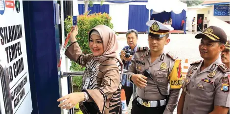  ?? ADI WIJAYA/JAWA POS ?? INOVASI CERDAS: Prof Diah Natalisa mencoba pintu khusus Satpas SIM Satlantas Polres Gresik dengan disaksikan AKP Wikha Ardilestan­to (tengah) dan Kapolres AKBP Boro Windu Danandito (kanan) kemarin. Pintu itu hanya bisa dibuka dengan kartu khusus yang...