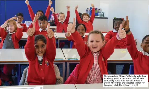  ??  ?? These pupils at St Mary’s Catholic Voluntary Academy give the thumbs-up to their new temporary home at St James’s House in Derby, where they are expected to stay for two years while the school is rebuilt