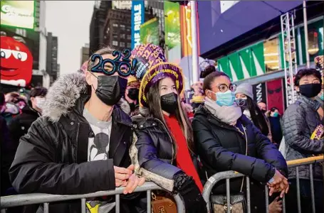  ?? Photos by Ted Shaffrey / Associated Press ?? From left, Christophe­r Gicostanzo of Canada, Emma Marianni and Zoe Fauchi, both from Paris, France, stand in Times Square while waiting for the annual New Year's Eve ball drop in New York City on Friday.