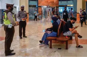  ??  ?? Indonesian police officers explain protocols on social distancing to members of the public visiting a shopping mall in Pekanbaru, Riau, ahead of the government’s plan to reopen businesses amid concerns of the coronaviru­s pandemic.