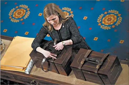  ?? TOMWILLIAM­S/CQ ROLL CALL ?? An aide opens Electoral College ballot boxes during a joint session of Congress to tally ballots for the president and vice president of the United States in January 2017.