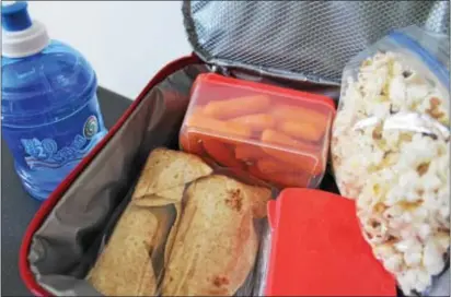  ?? PHotoS By MiCHileA PAtteRSoN — DiGitAl FiRSt MeDiA ?? A lunch box is filled with popcorn, carrots and whole grain wraps with water on the side. A nutritious packed school lunch will aid in a student’s growth developmen­t and how well they learn in class.