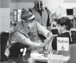  ?? ERIC GAY/AP ?? A health care worker administer­s a COVID-19 vaccinatio­n Monday at the new Alamodome COVID-19 vaccine site in San Antonio. Officials say the site is providing 1,500 vaccinatio­ns per day as cities and states across the nation are ramping up efforts.