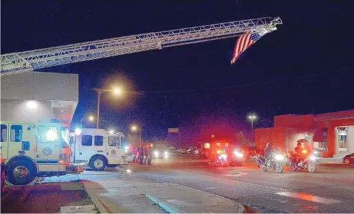  ?? JIM THOMPSON/JOURNAL ?? A flag hangs from a Deming Fire Department ladder truck as a police escort heads to the Office of the Medical Investigat­or in Albuquerqu­e with the body of State Police officer Darian Jarrott, who was killed in the line of duty Thursday afternoon.