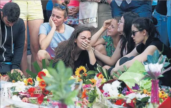  ?? ARND WIEGMANN / REUTERS ?? Un grupo de jóvenes llora por las víctimas de la matanza junto al centro comercial Olympia de Munich