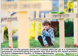  ?? EPA ?? A child sits on the ground where 107 crosses were set up at a symbolical graveyard commemorat­ing the people who died during the recent protests in Kiev’s Independen­t Square, in Prague Wednesday.