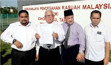  ??  ?? Khairuddin (second left) shows the report to media outside state MACC office. — Bernama photo